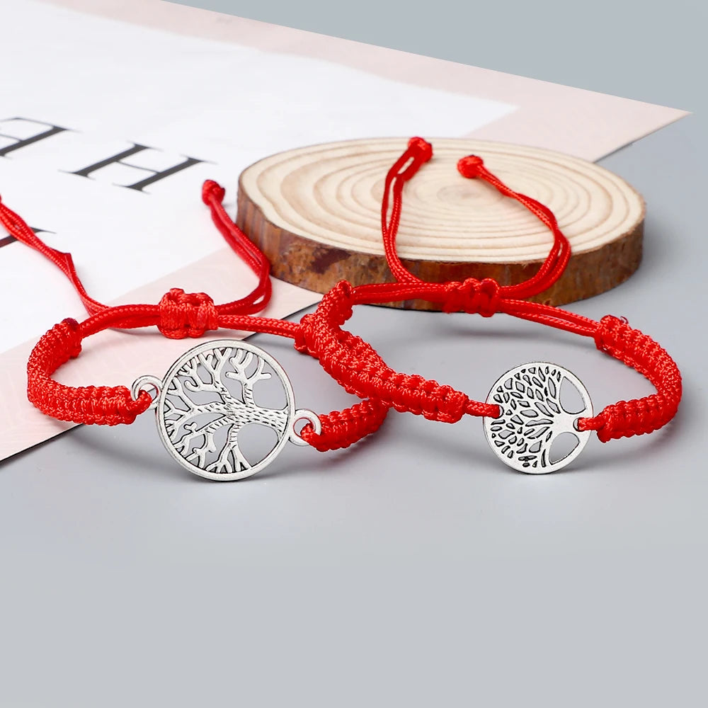 Duo de bracelets Arbre de Vie tressés en cordon rouge, posés devant une rondelle de bois, breloques arbre de vie argentées