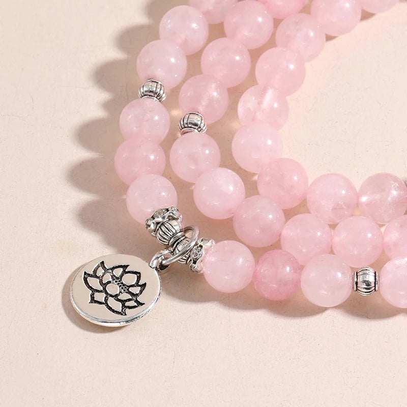 Gros plan sur la breloque Lotus argentée et les perles de quartz rose du bracelet mala