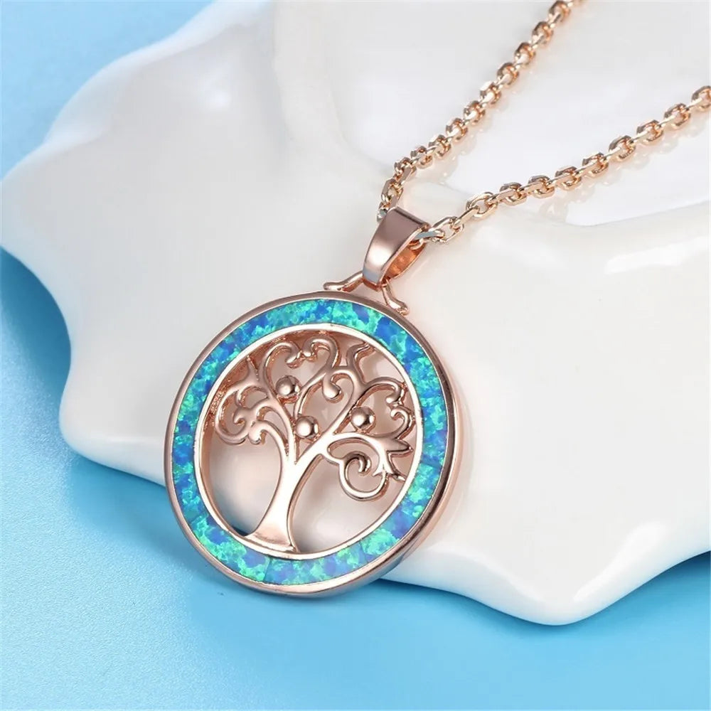 Pendentif Arbre de Vie en gros plan, motif ajouré doré rose sur fond de pierre opaline bleu-vert