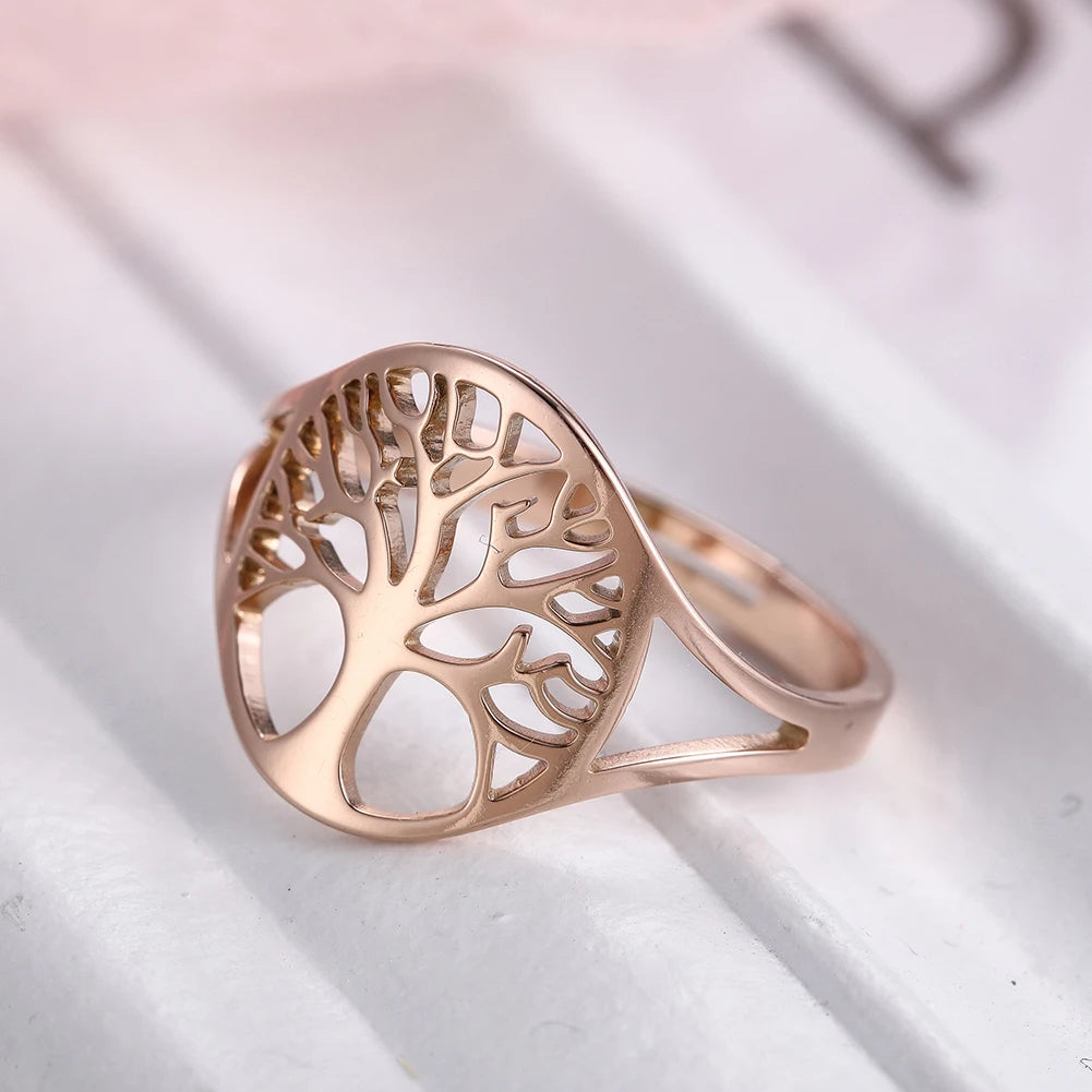 Bague Arbre de Vie ajourée en acier doré rose, posée en gros plan sur un tissu clair, vue de profil