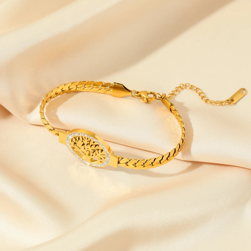 Bracelet Arbre de Vie en acier doré à maillons tressés, posé sur un tissu satiné beige