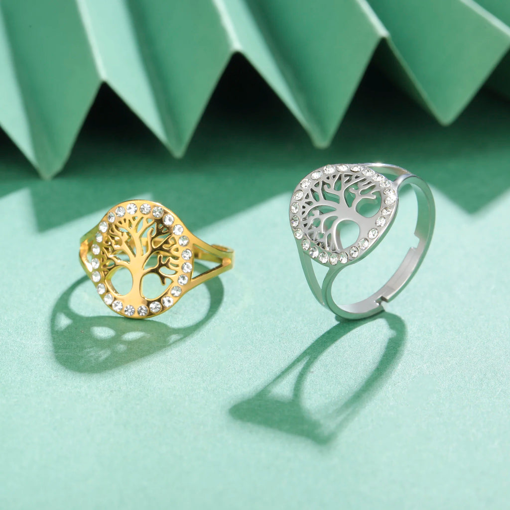Bague Arbre de Vie en acier doré et sa version argentée, posées côte à côte sur un fond vert