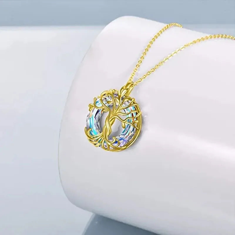 Collier Arbre de Vie Celtique en finition dorée, cercle en cristal multicolore, posé sur un support blanc incurvé
