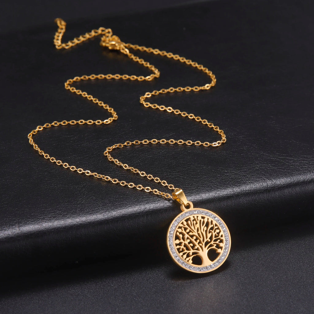 Pendentif Arbre de Vie doré serti de strass sur chaîne fine, posé sur fond noir
