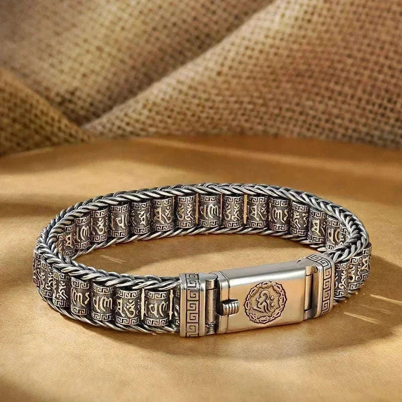 Bracelet jonc en argent porté au poignet fermé en poing, bagues assorties