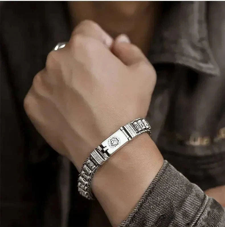 Bracelet jonc en argent à maillons gravés, vue rapprochée sur fond beige texturé