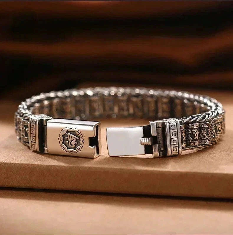 Gros plan sur le fermoir à cliquet du bracelet jonc, gravures de mantras et motifs grecques